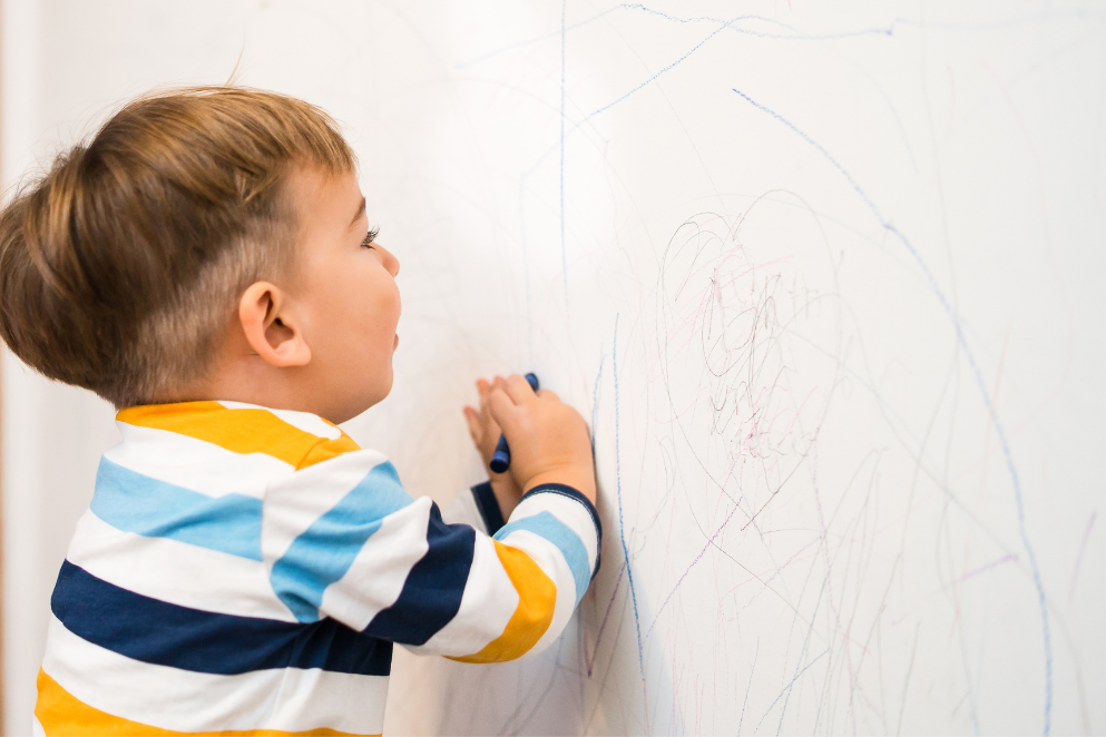 Dziecko brudzące ścianę kredką świecową