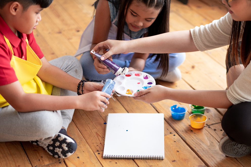 Mama nakładająca farbki z tubek na paletę i dwójka dzieci
