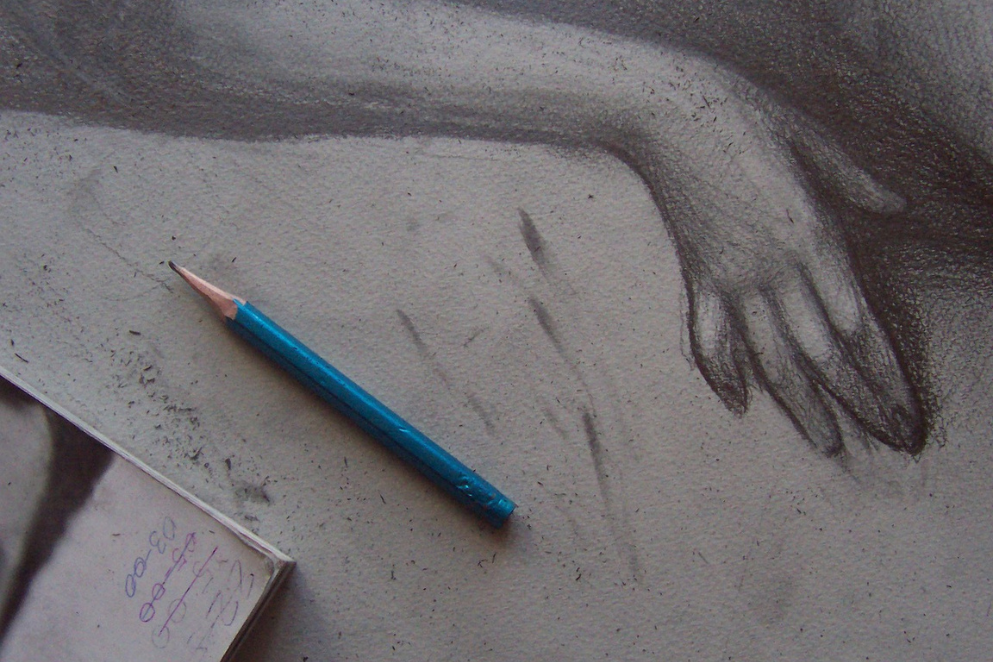 Ołówek leżący na papierze, na którym narysowana jest ręka