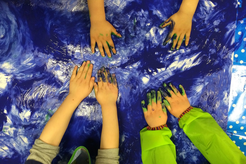 Umazane farbą dziecięce dłonie leżące na płótnie